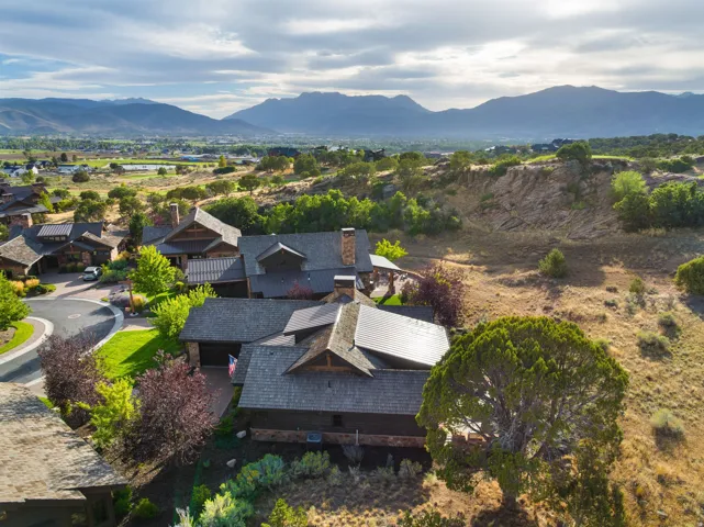 Expansive property featuring a multi-level structure with multiple gables, a dark-toned roof, and surrounding natural landscaping