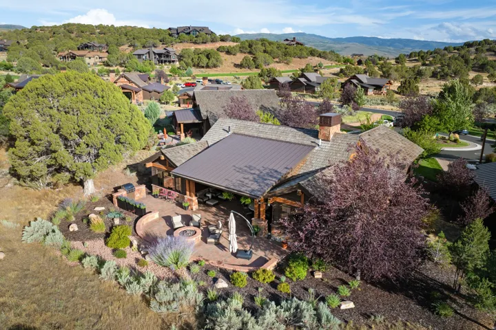 Exterior property featuring a multi-level roofline, extensive outdoor patio, built-in fire pit, covered outdoor living space, and mature landscaping