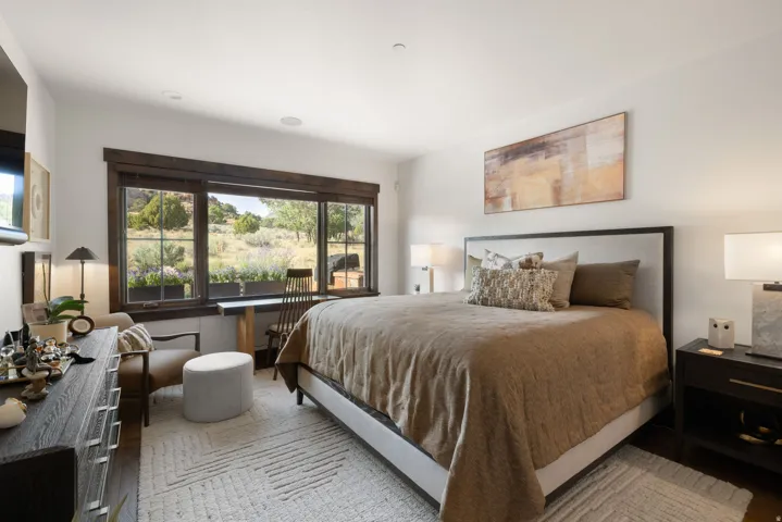 Expansive multi-pane window with dark wood trim, recessed ceiling lighting, wood-finish flooring, and a built-in desk