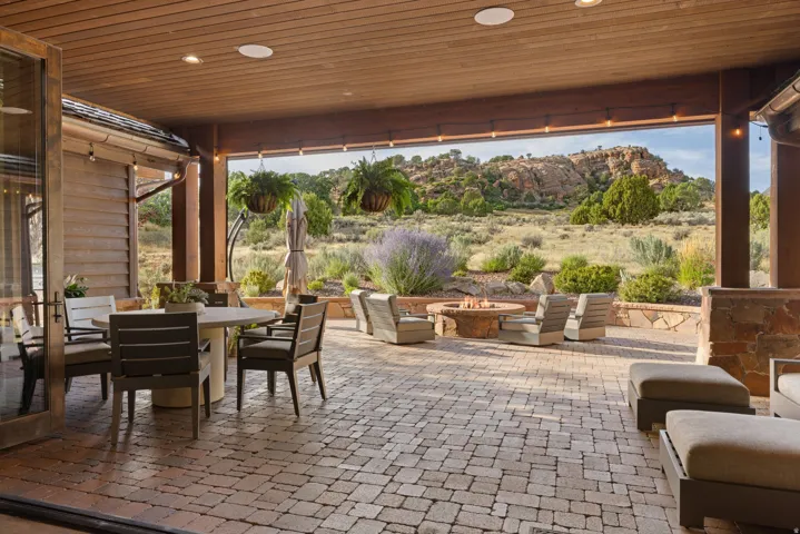 Expansive covered patio featuring a wood-panel ceiling, recessed lighting, and paver flooring