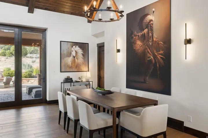 Exposed wood ceiling beams, wood-finish flooring, and a wrought iron chandelier
