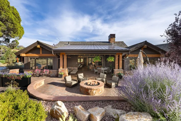 Expansive patio with a built-in stone fire pit, covered outdoor living area, and mature landscaping