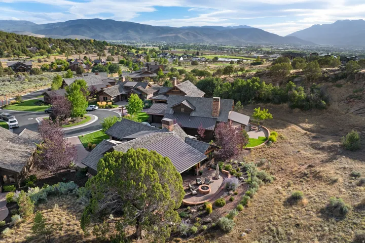 Extensive property featuring a multi-level structure with a covered patio, a circular hardscape patio with a built-in fire pit, and landscaped grounds