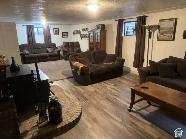 Multi-purpose room featuring wood-finish flooring, a brick hearth, a built-in wood-burning stove, and recessed lighting