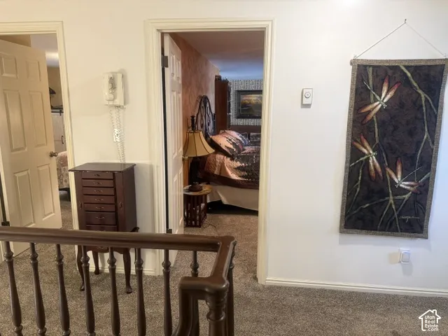 Stained wood balustrade featuring decorative turned spindles, dual white-paneled interior doors, and wall-mounted intercom system