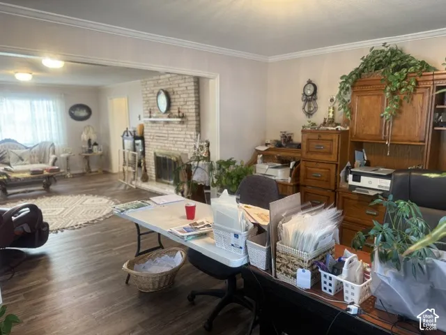 Living area featuring wood-finish flooring, floor-to-ceiling brick fireplace with a mantel, and crown molding