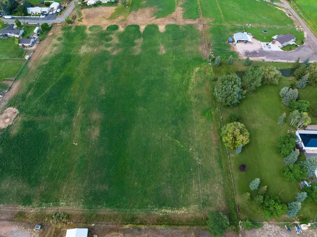Expansive green field with surrounding residential properties, mature trees, and landscaping