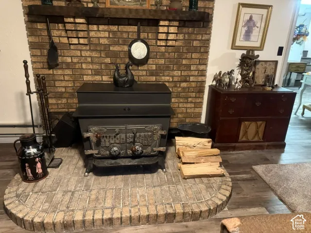 Full-height brick masonry fireplace featuring a wood-burning stove insert, decorative wood mantel, and a rounded brick hearth with wood-finish flooring