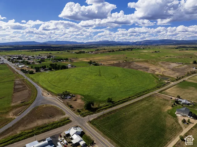 Expansive green fields with circular crop patterns, bordered by paved roadways