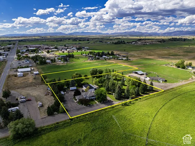 Expansive property featuring multiple structures, mature trees, and a paved circular drive