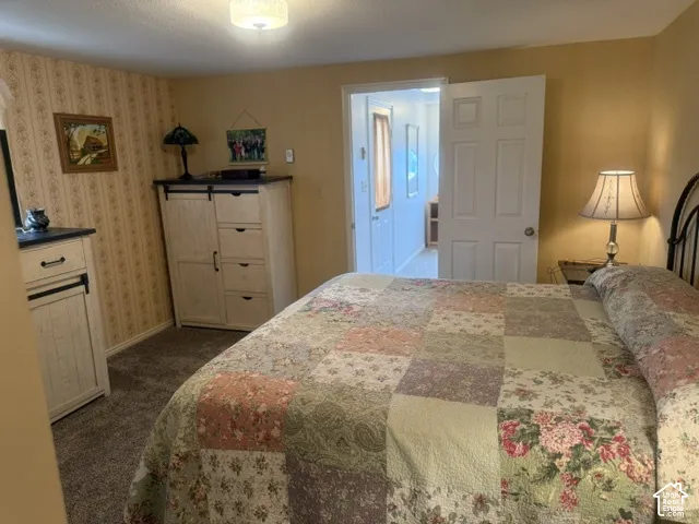Room featuring patterned wallpaper, carpeted flooring, a six-panel interior door, and a flush-mount ceiling fixture