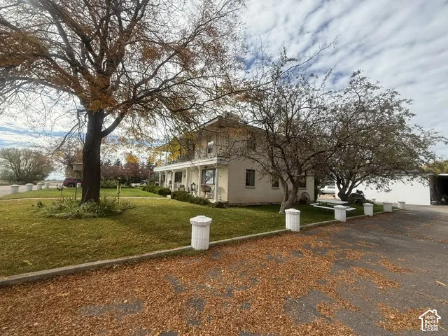 Two-story masonry exterior featuring a covered front porch, upper-level balcony, and mature trees on a landscaped lot