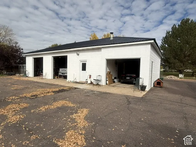 Detached three-bay garage structure featuring a painted masonry exterior, a metal roof, and an asphalt driveway