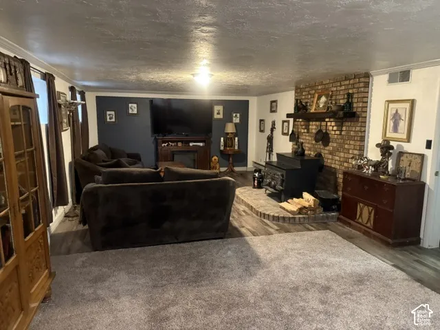 Floor-to-ceiling brick fireplace surround, wood-burning stove, raised stone hearth, thick timber mantel, and wood-finish flooring
