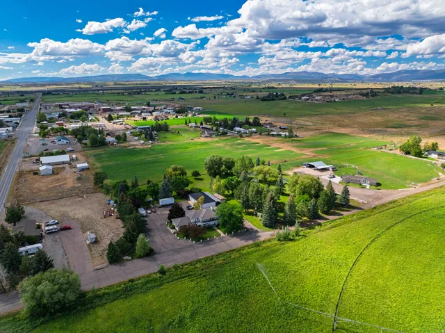 Expansive green landscape with distant mountains, a developed roadway, and scattered structures