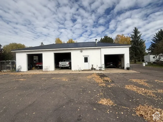 Detached structure featuring a white masonry exterior, metal roof, and three open garage bays