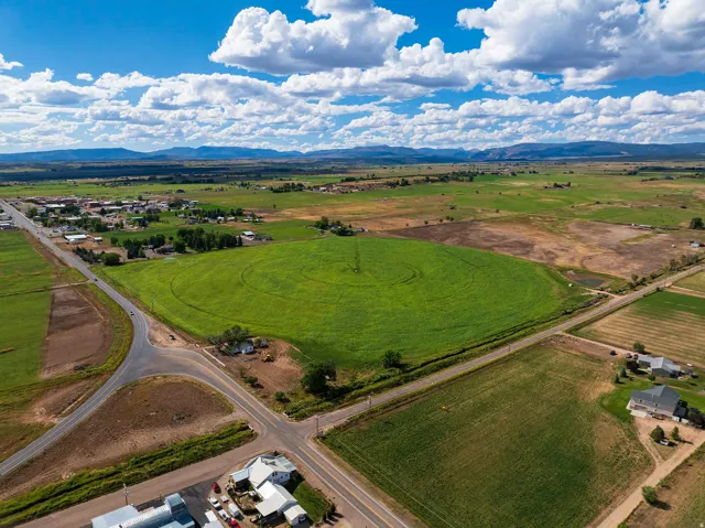 Expansive green fields with circular crop patterns, bordered by paved roadways