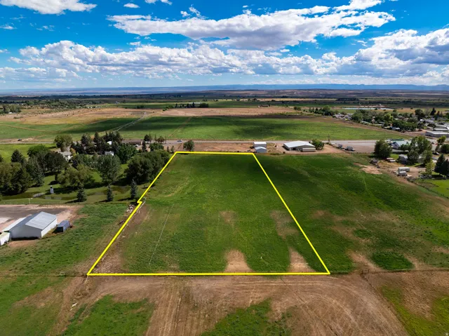 Expansive open land with delineated boundaries, surrounded by agricultural fields and distant structures