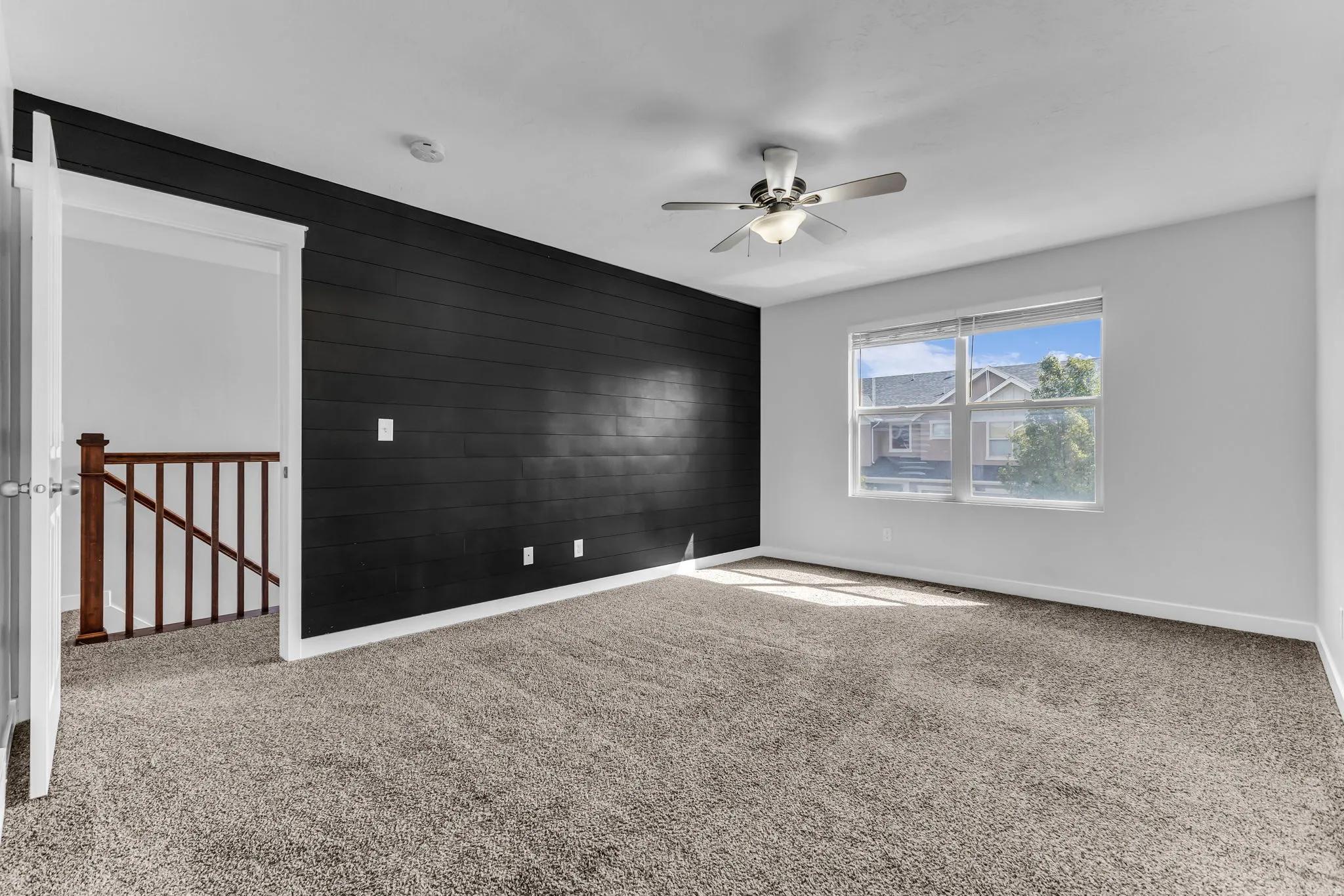 Carpeted room with a dark shiplap accent wall, white painted walls, and a ceiling fan with integrated lighting