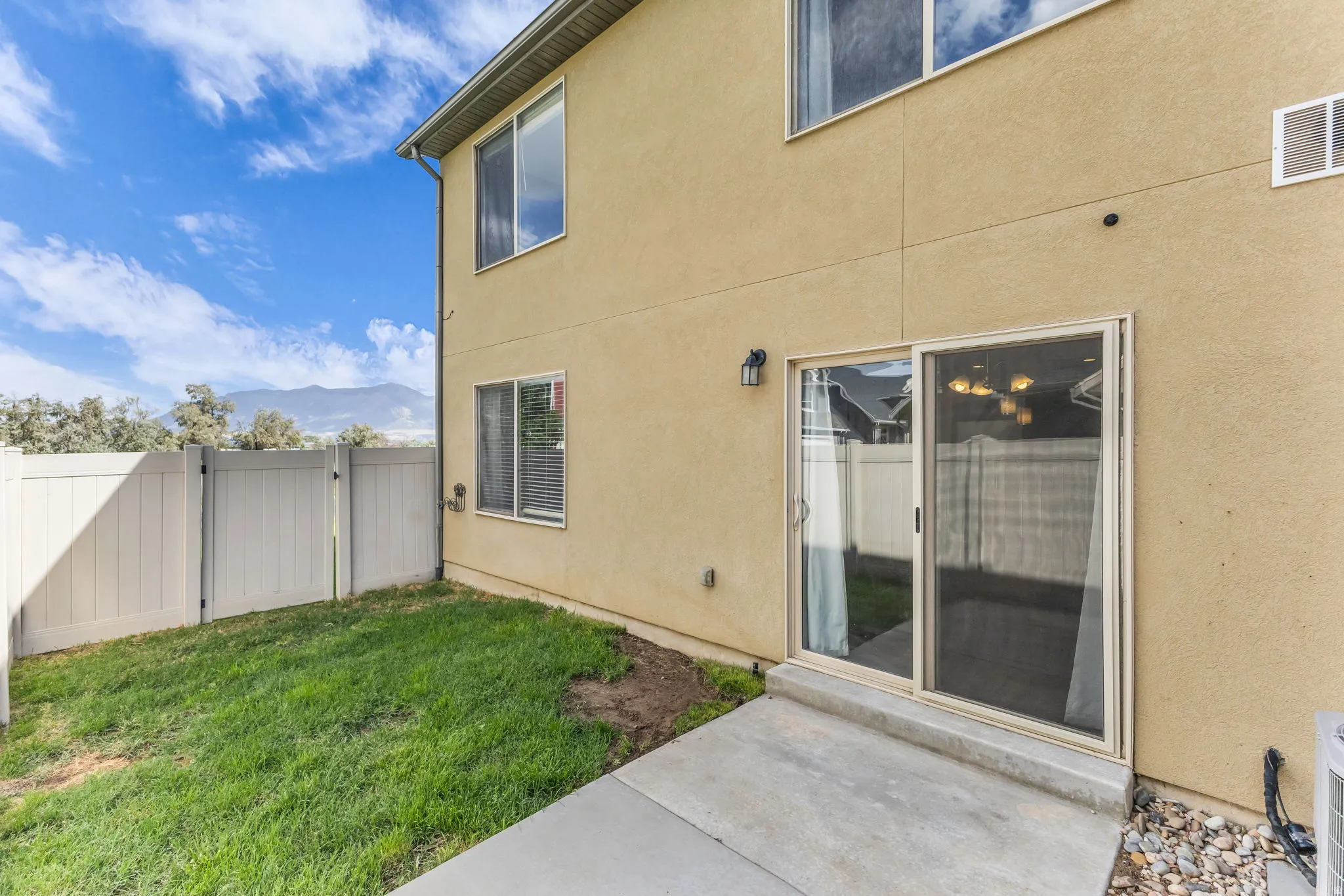 Stucco exterior featuring multiple windows and a sliding glass door