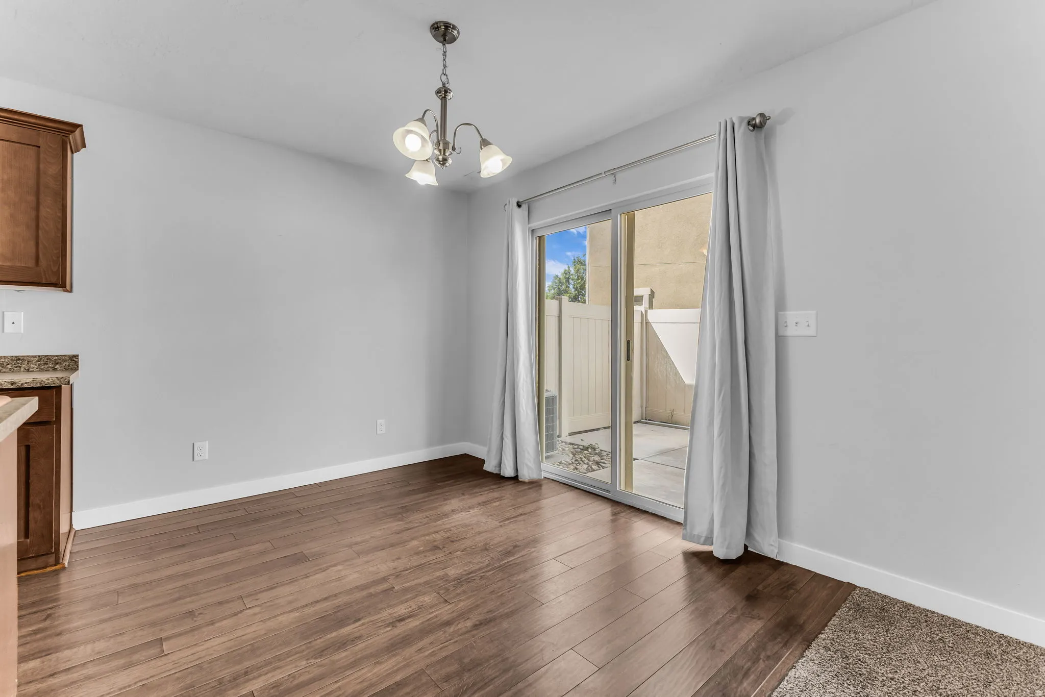 Wood-finish flooring, sliding glass patio door, built-in cabinetry, granite-style countertops, and a ceiling-mounted light fixture