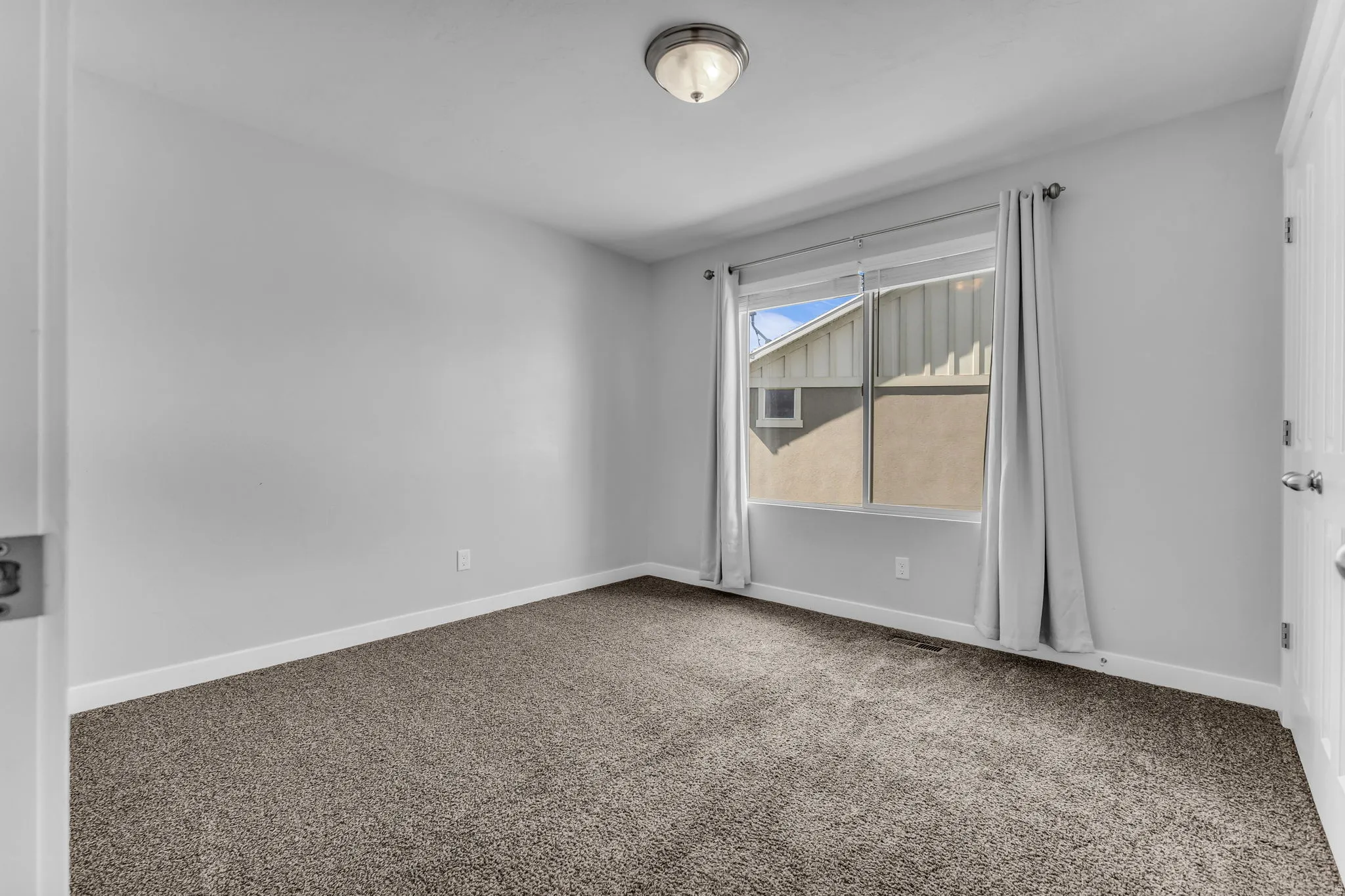 Wall-to-wall carpeting, white baseboards, and a single window with white trim