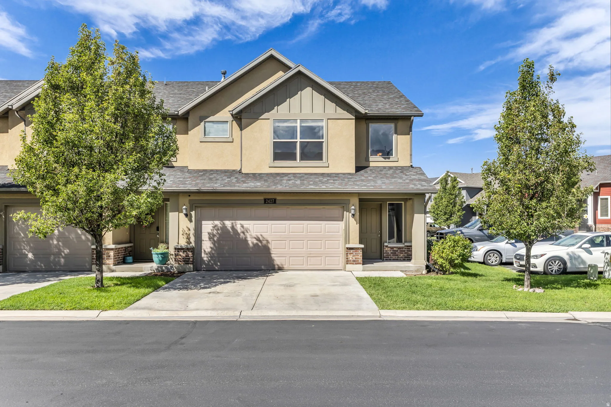 Two-story stucco exterior with stone accents, a two-car garage, and a covered entry