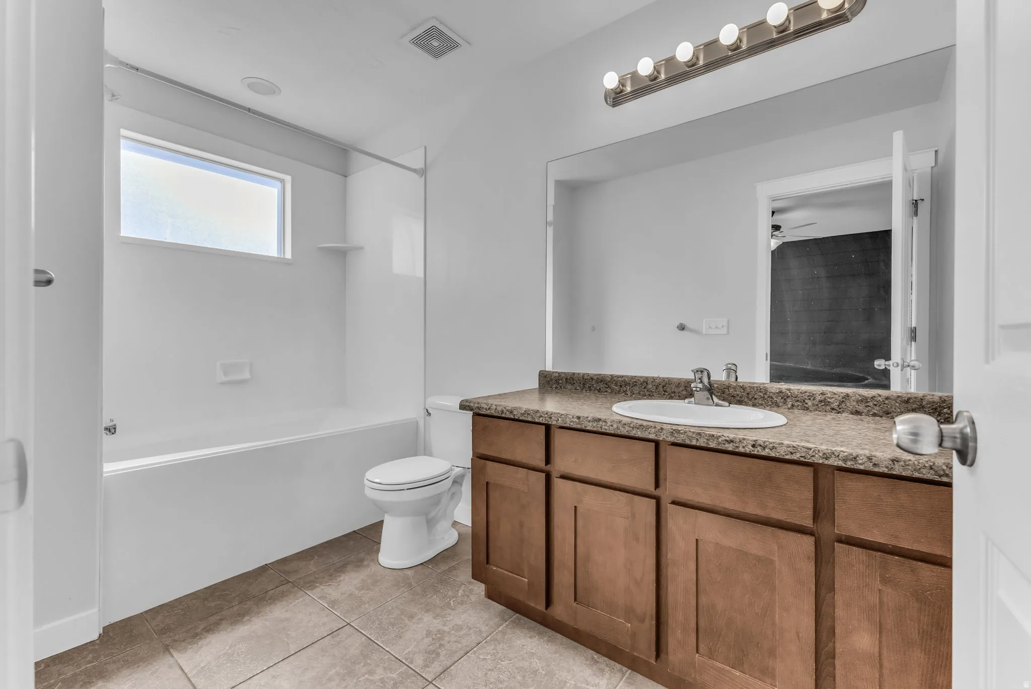 Bathroom featuring a single vanity with wood-finish cabinetry, a white oval sink, and a speckled countertop