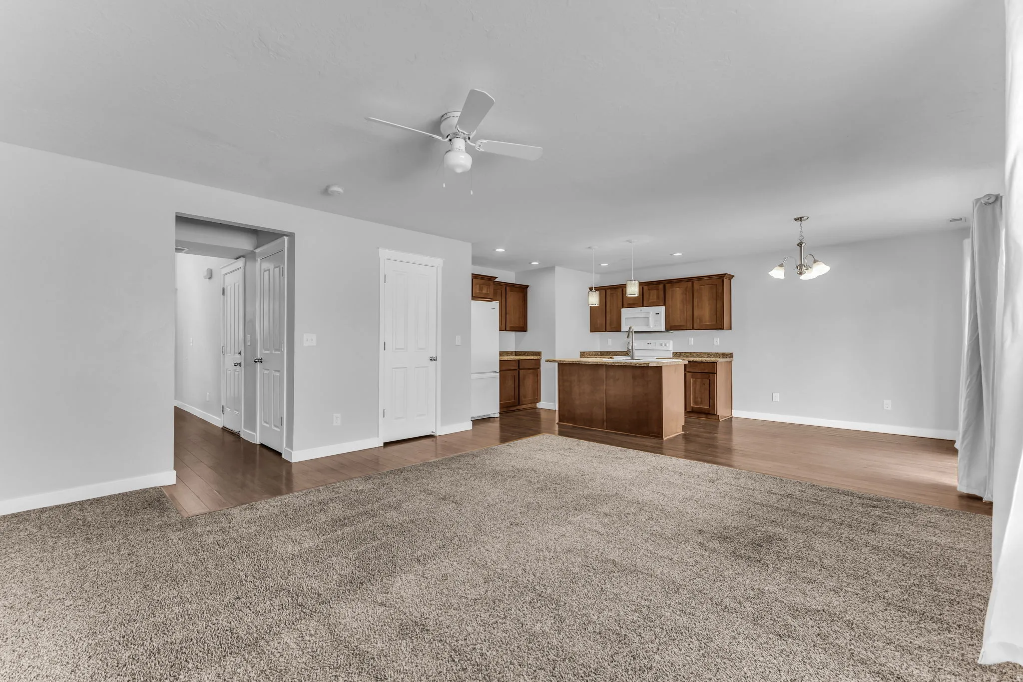Expansive room with neutral carpeting and wood-finish flooring