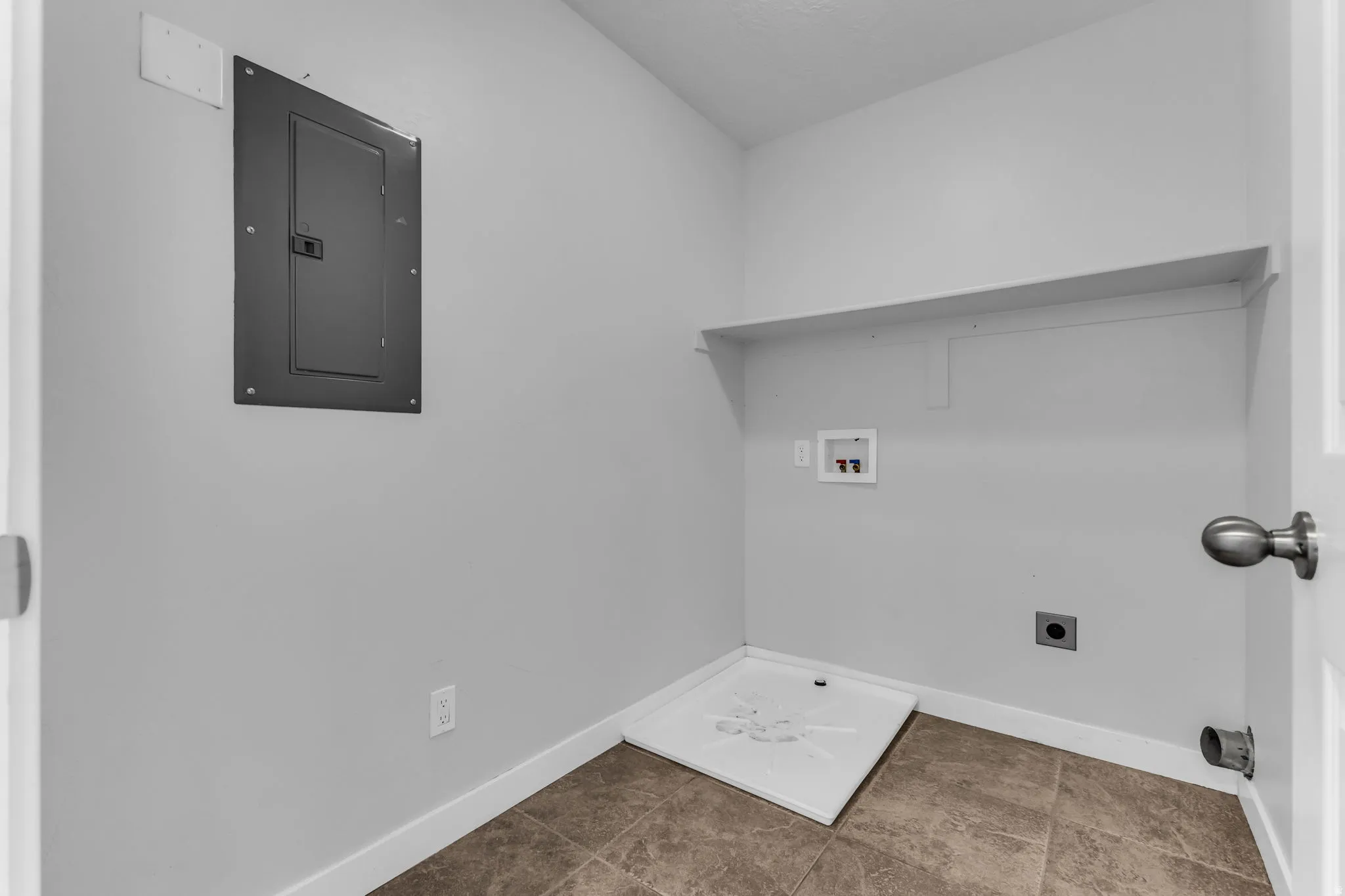 Utility room featuring tile flooring, a wall-mounted shelf, and appliance hookups