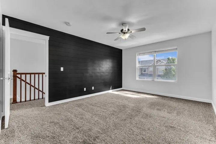 Carpeted room with a dark shiplap accent wall, white painted walls, and a ceiling fan with integrated lighting