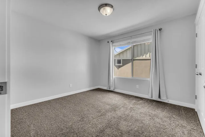 Wall-to-wall carpeting, white baseboards, and a single window with white trim