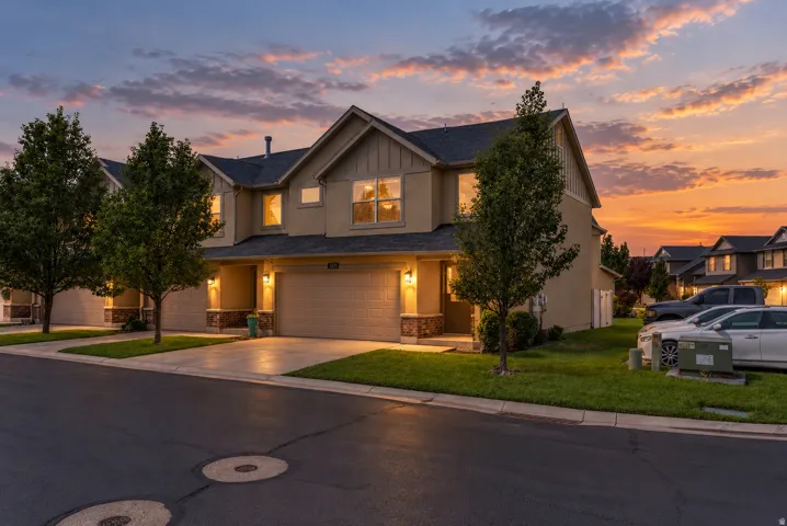 Stucco exterior with stone accents, attached two-car garage, concrete driveway, and mature landscaping