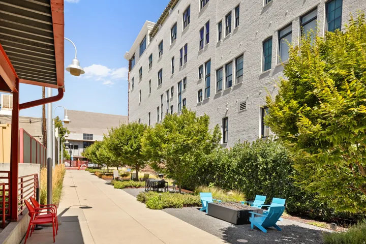 Ground-level outdoor space featuring a paved walkway, mature trees, and landscaping elements