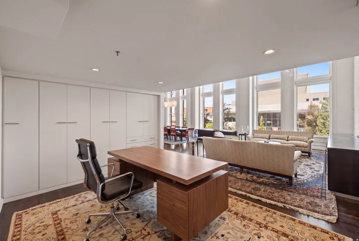 Wall of custom built-in cabinetry, wood-finish flooring, recessed lighting, and expansive windows