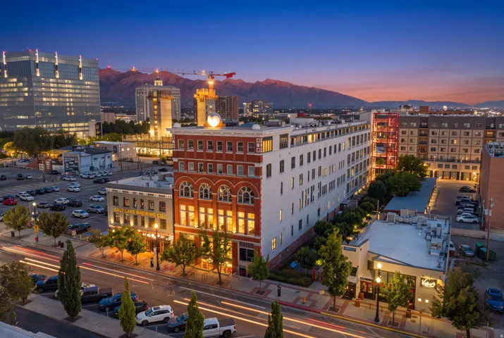 Downtown urban setting with multiple commercial and residential buildings, mountain backdrop, and tree-lined streets