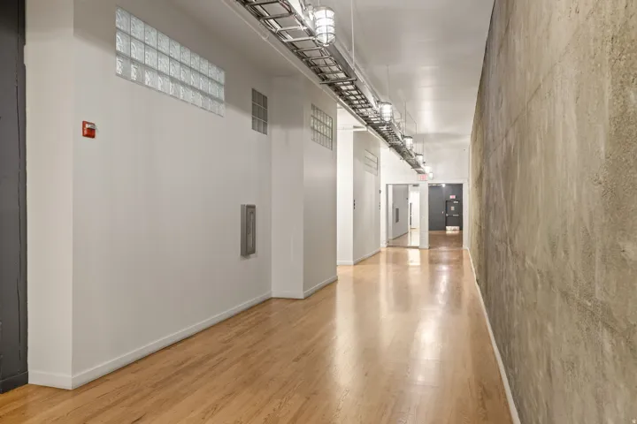 Wood-finish flooring, exposed concrete wall, glass block accents, and industrial-style ceiling lighting