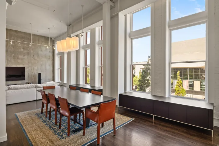 Hardwood flooring complemented by a concrete accent wall and high ceilings