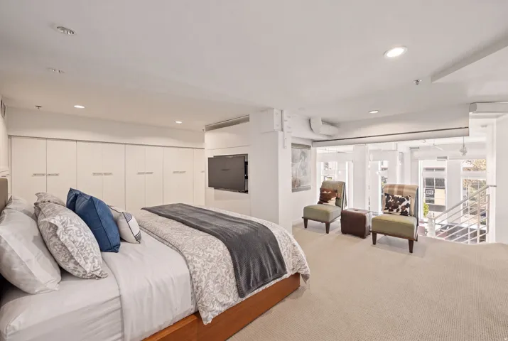 Wall-mounted television with built-in cabinetry, recessed lighting, and carpeted flooring