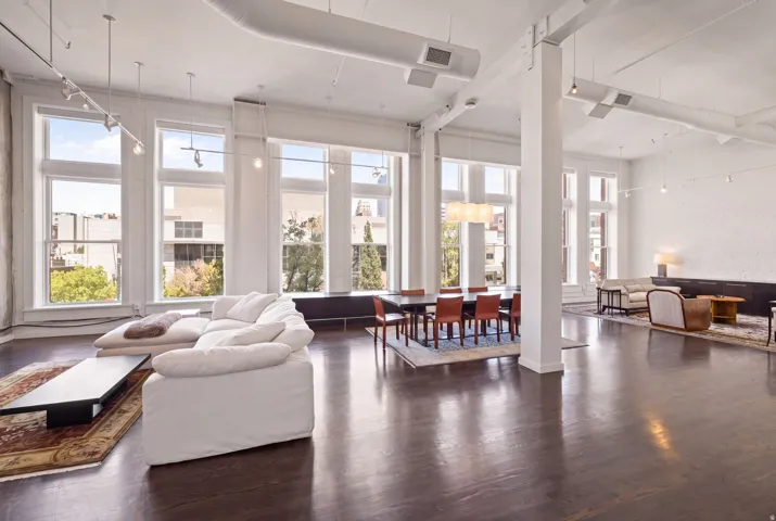 Expansive open-concept space featuring high ceilings, exposed ductwork, large multi-pane windows, and dark wood-finish flooring