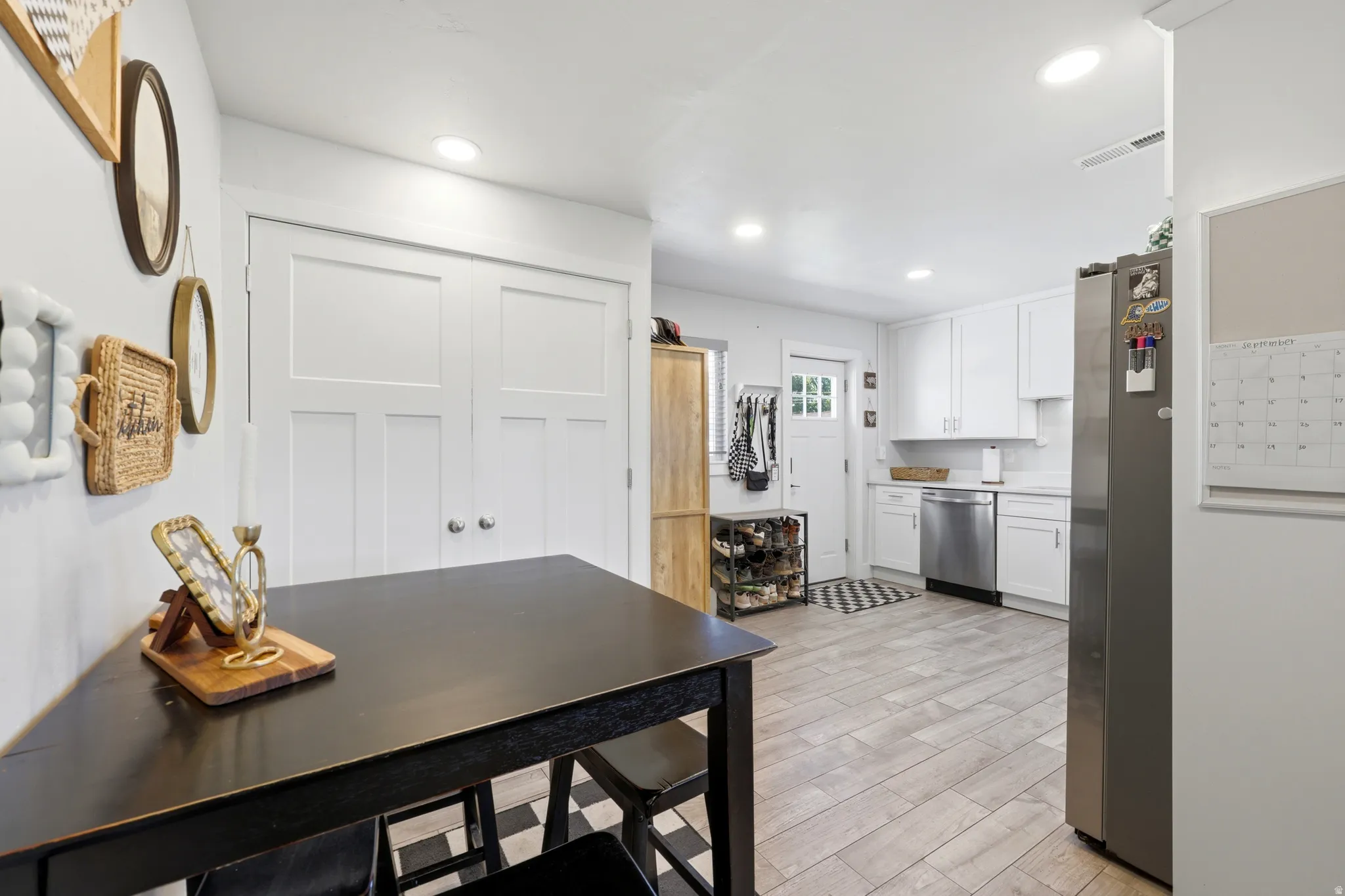 White shaker cabinetry with stainless steel appliances, light wood-finish flooring, and recessed ceiling lighting