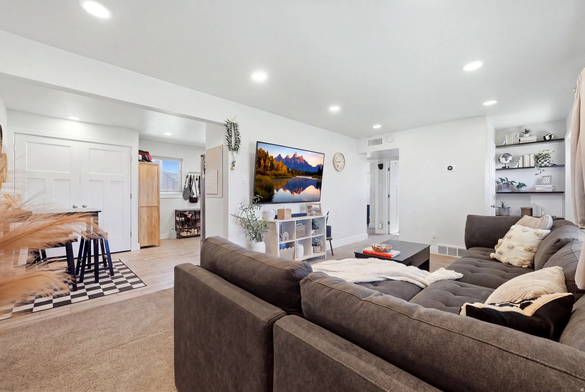 Recessed lighting, light-toned carpeting, built-in shelving, white walls, and wood-finish flooring