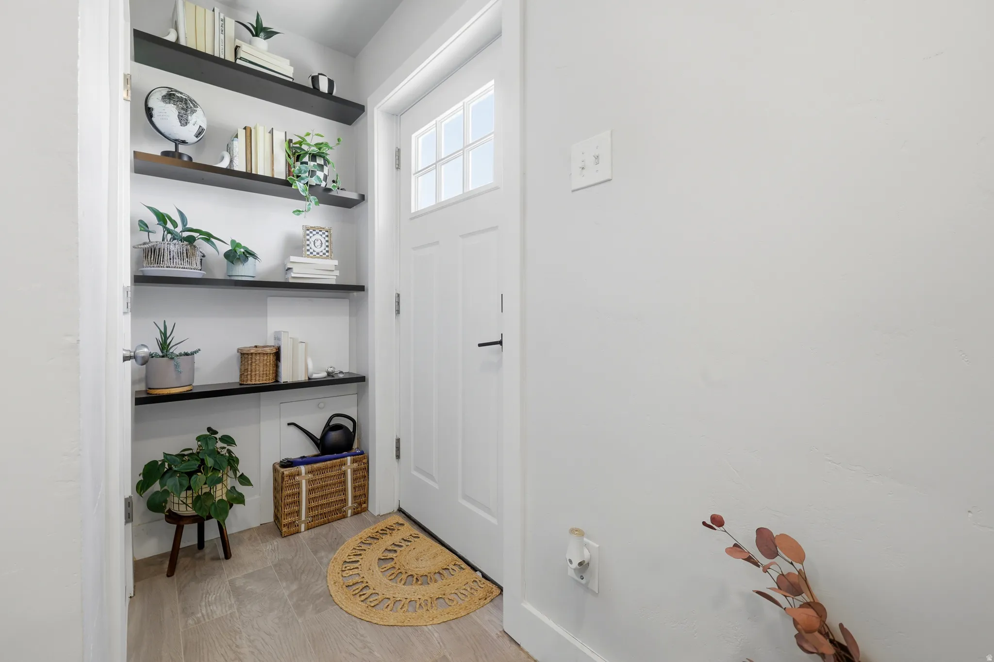 Entryway with wood-finish flooring, built-in shelving, and a white door with window panes