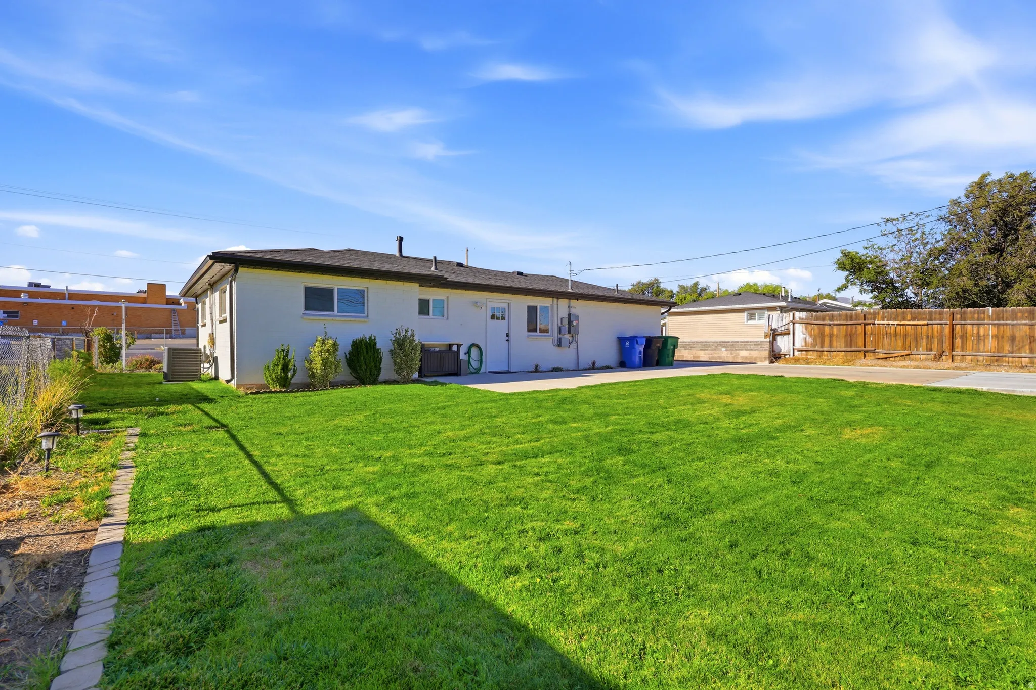 Expansive green lawn, white exterior siding, paved patio area, and wood privacy fencing