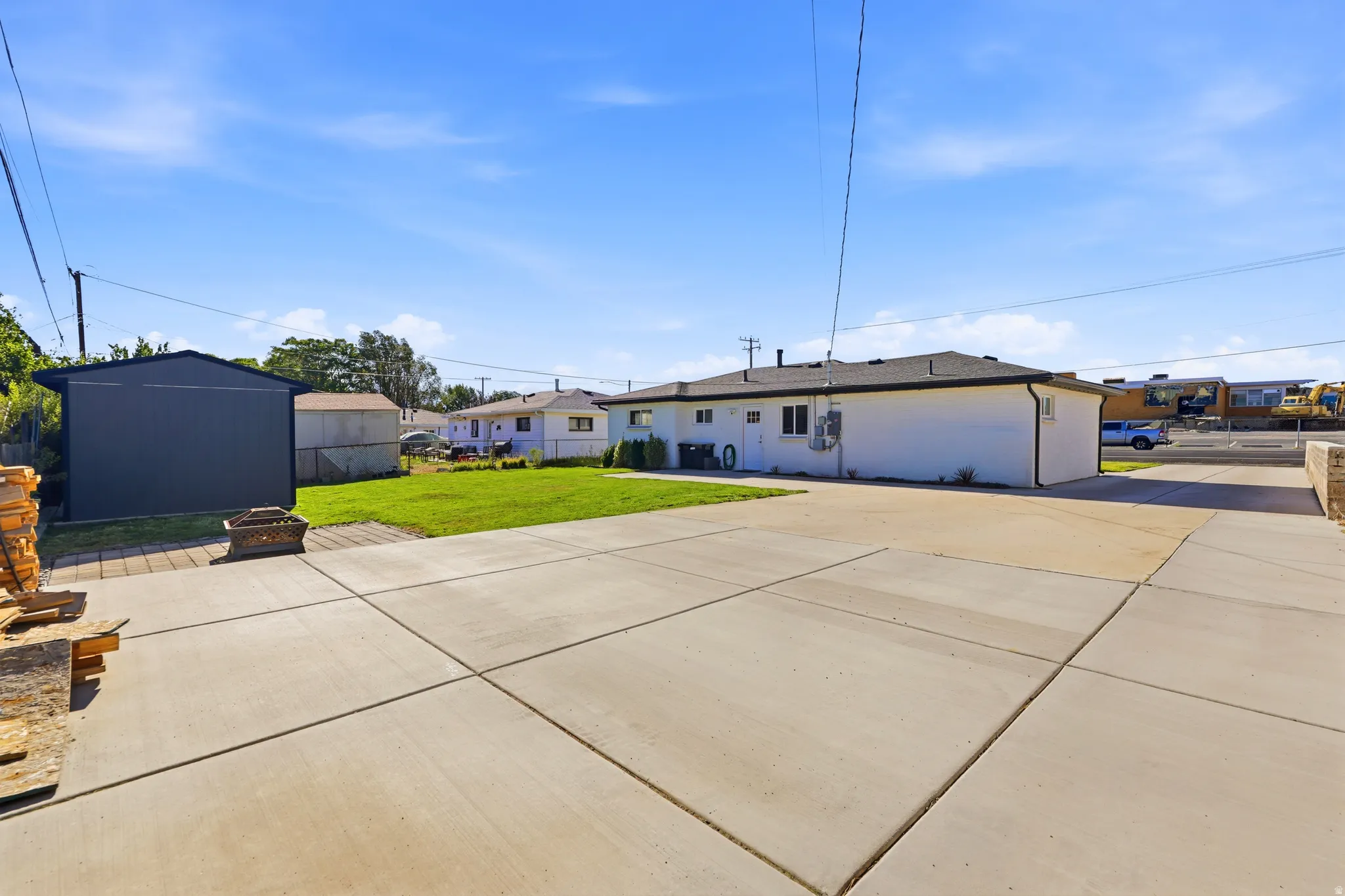 Expansive concrete patio, a detached storage shed, and a manicured lawn area