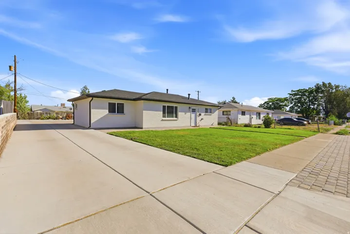 Spacious concrete driveway, manicured lawn, and paved sidewalk