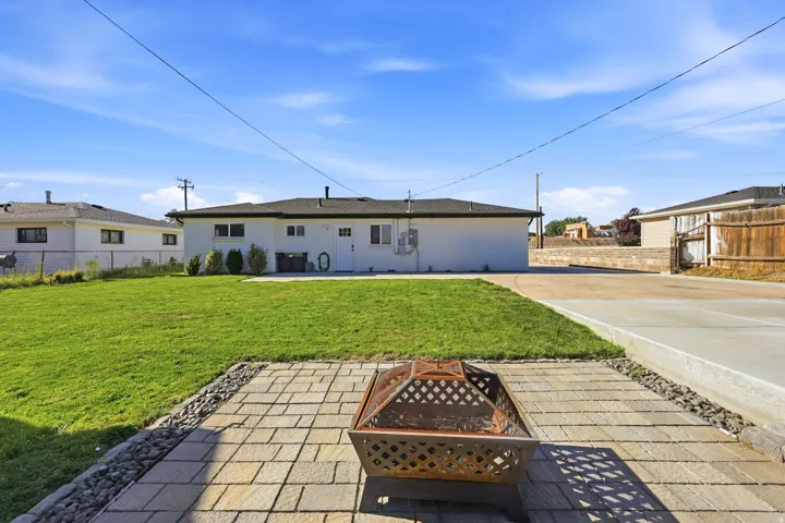 Expansive backyard featuring a lush lawn, paver patio, and a fire pit