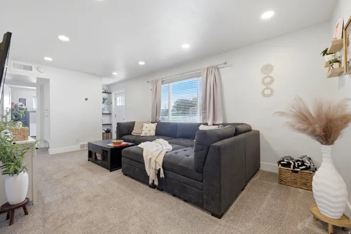 Recessed lighting, light-toned carpeting, and a large window with blinds