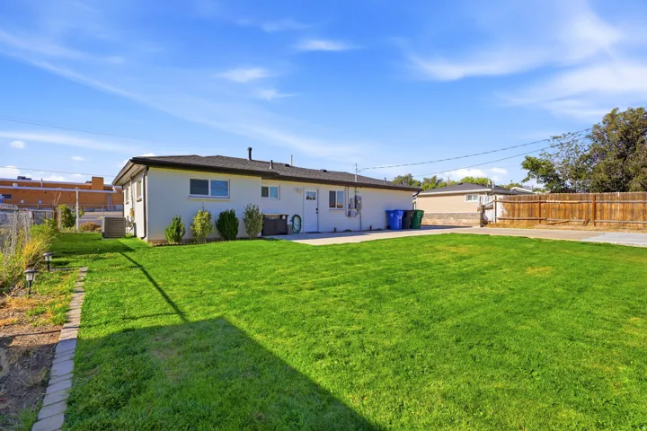 Expansive green lawn, white exterior siding, paved patio area, and wood privacy fencing