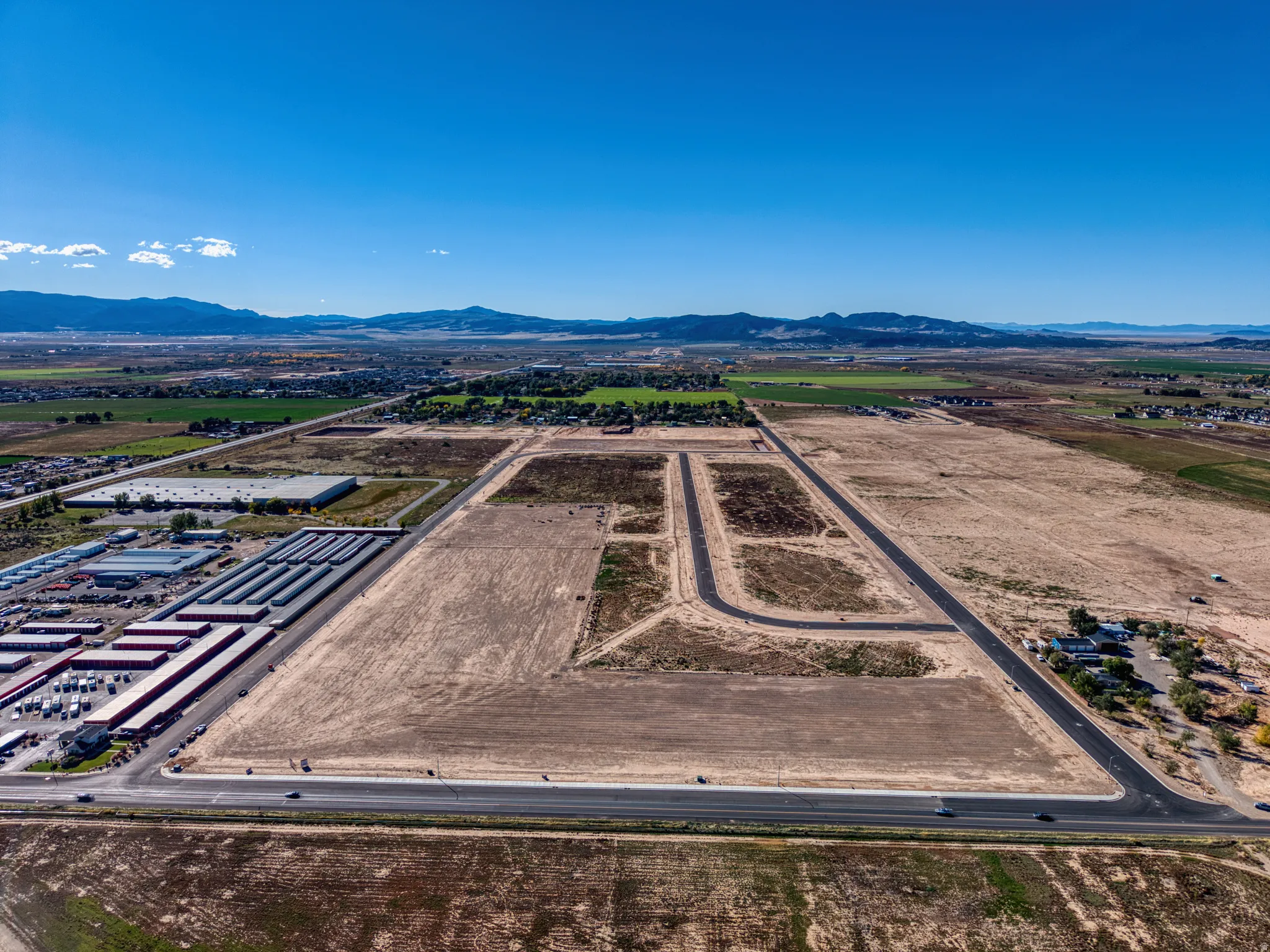 Expansive land parcel with established road infrastructure, visible mountain backdrop, and nearby commercial facilities